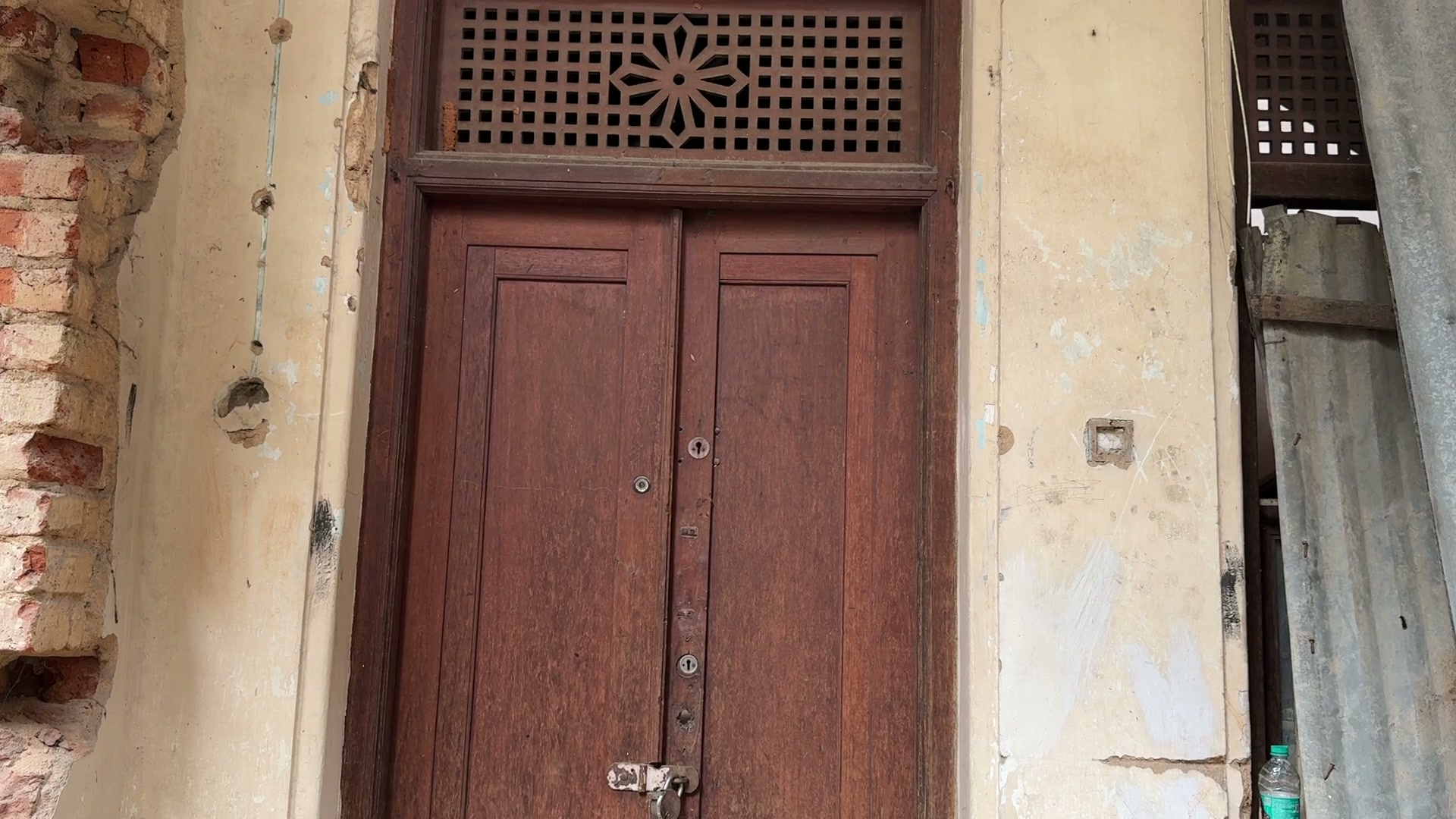 Teak doors beneath a carved jaali transom.