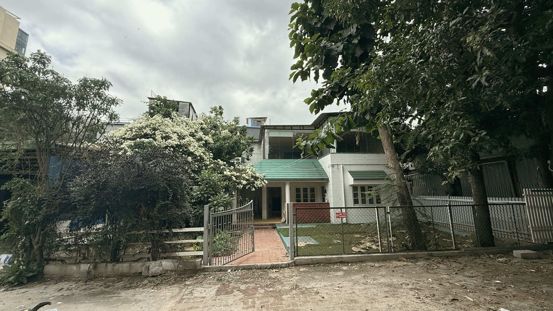 The sixty-year-old Brookefield bungalow behind its garden and mango trees.